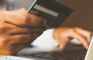 man holding his credit card to shop online