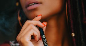 Close up of woman with manicured hand holding the clear vape pen