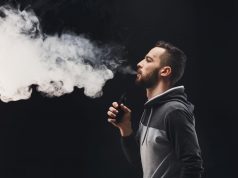 Young man vaping e-cigarette with vapour