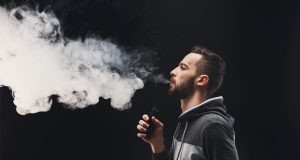 Young man vaping e-cigarette with vapour