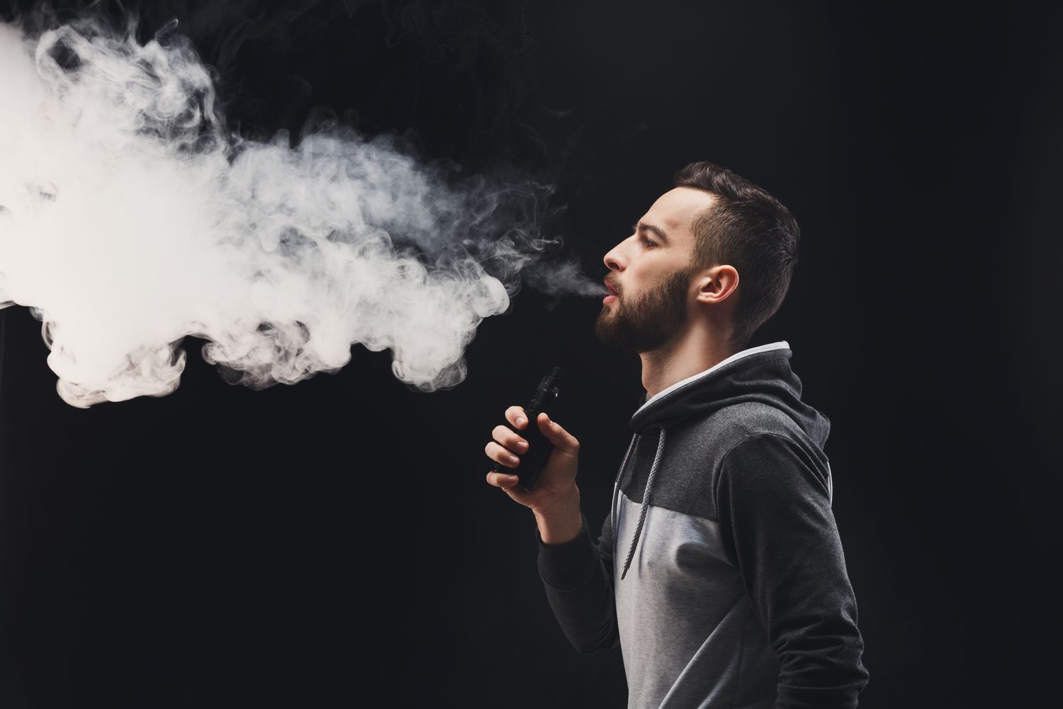 Young man vaping e-cigarette with vapour 
